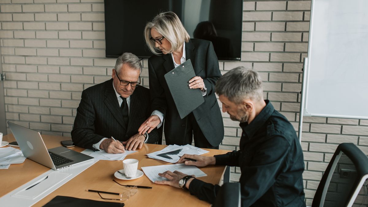 Professionals reviewing and signing documents in a meeting