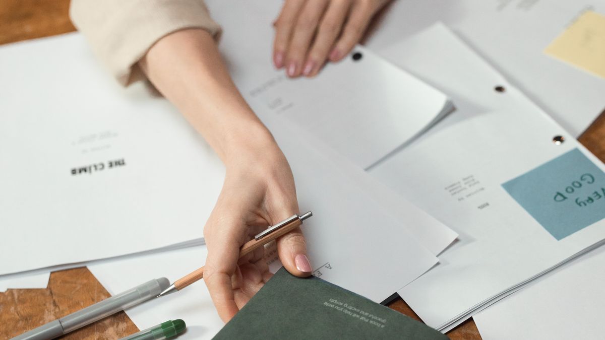Organizing papers on a desk with pens and a book