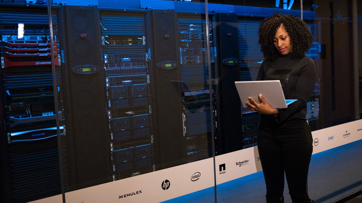 Engineer with laptop monitoring servers in a server room