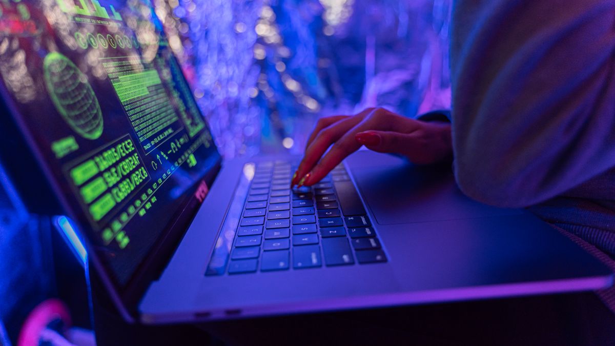 Hands typing on a laptop with cybersecurity graphics